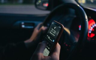 man holding cell phone in hand while driving