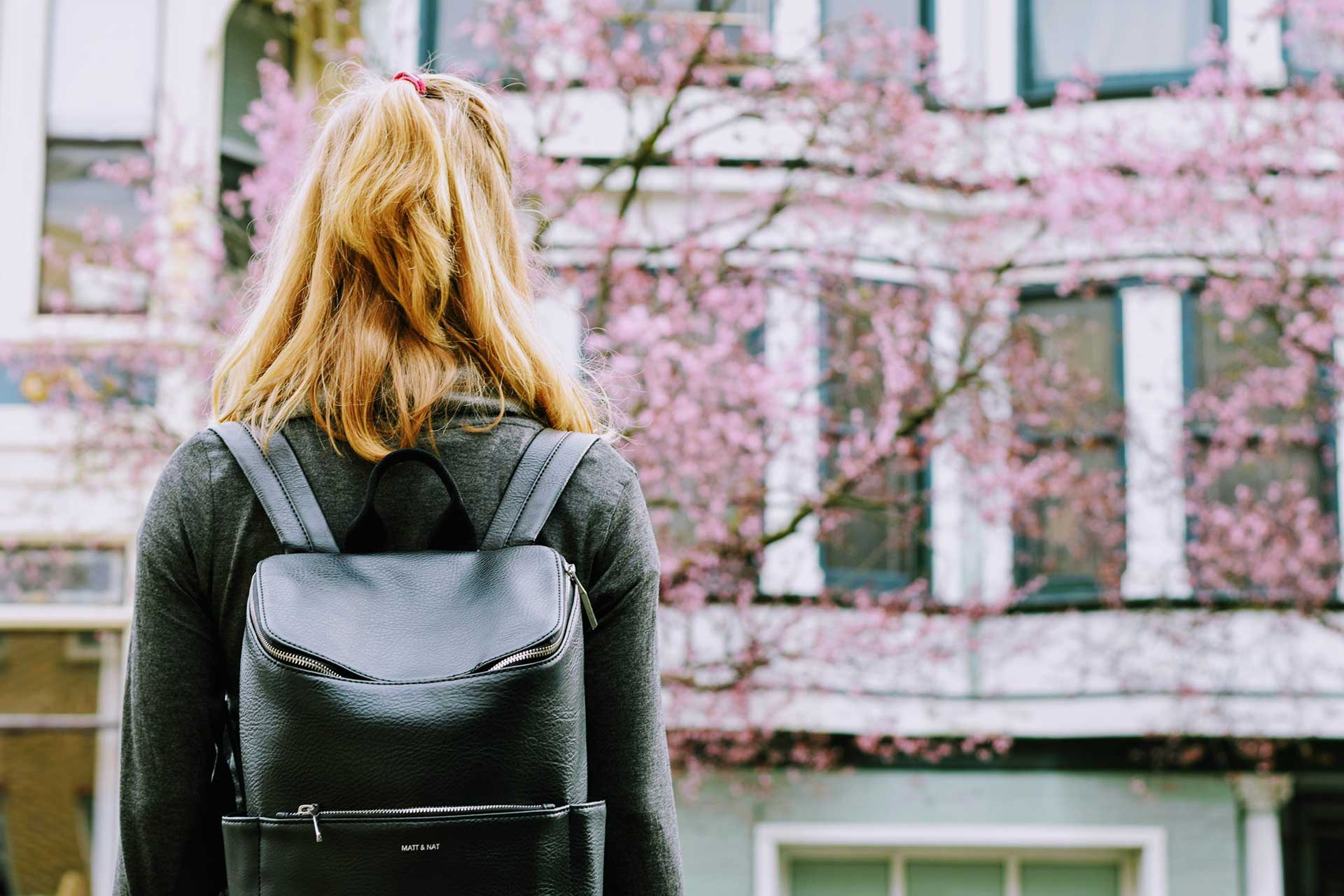 young women wearing a black backpack and facing away from camera