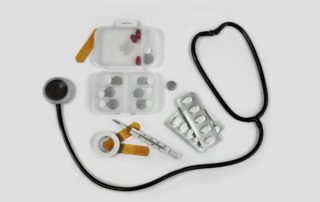 a stethoscope, pills, band-aides and other medical items on a white table