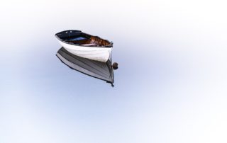 an empty row boat in mirrored water